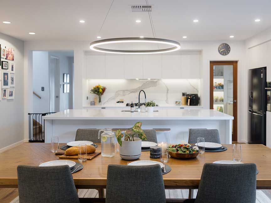 A well-lit kitchen with a wooden dining table and chairs.