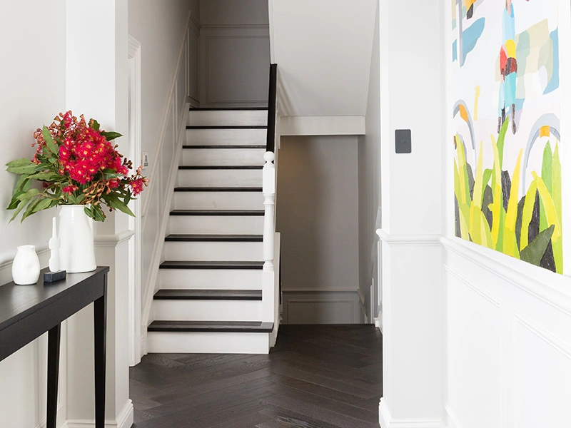 A cozy hallway adorned with a painting and a white staircase