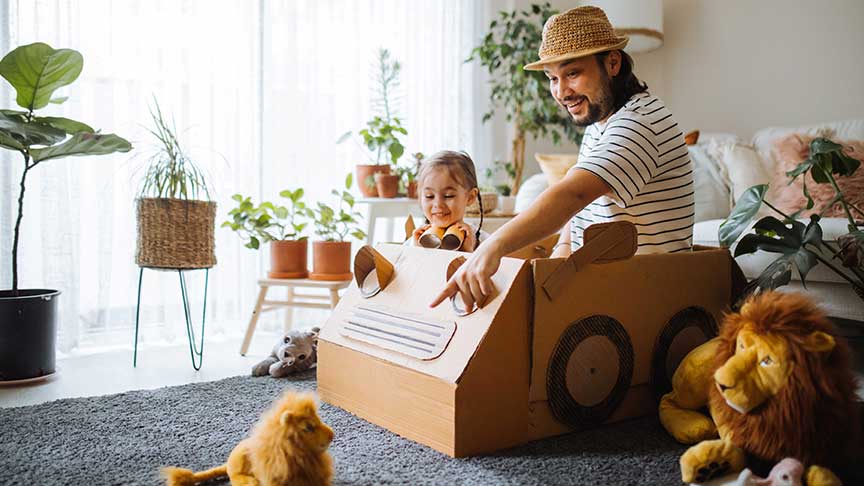 Father and daughter playing with a cardboard car