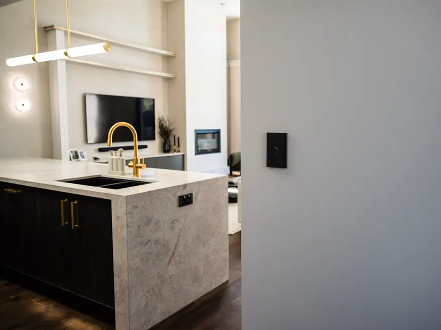 Modern kitchen with stainless steel sink and mounted TV.