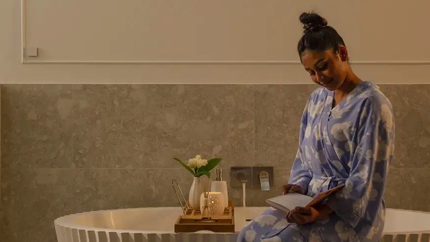 Woman sitting in a bathtub reading a book.