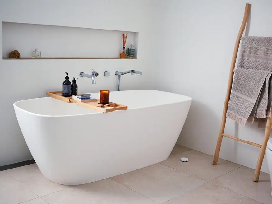 White bathtub with wooden tray. Tray holds bath accessories.