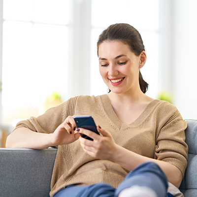 Smiling woman using her smartphone while sitting on the couch