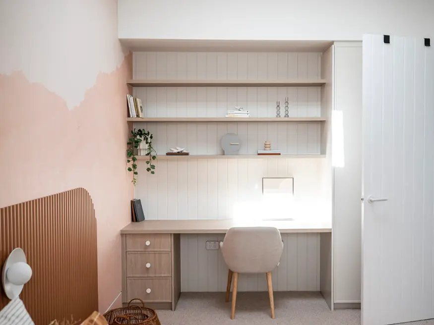 Desk with wall-mounted monitor, plant on surface.