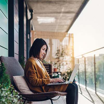 Woman on balcony couch using laptop