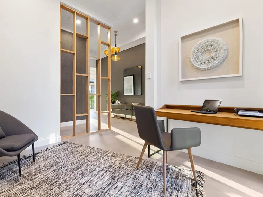 Home office with wooden desk, black chair, and rug.