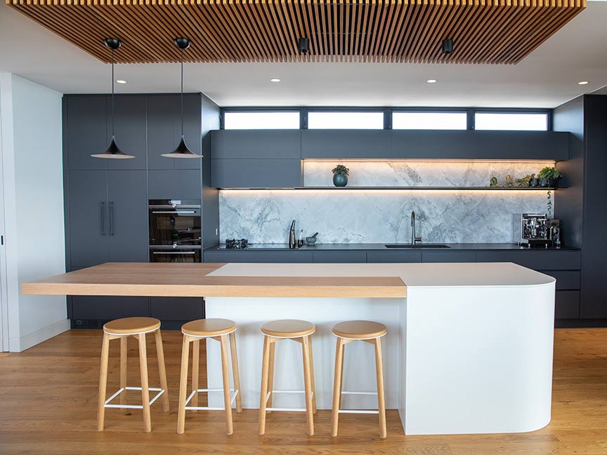 Modern charcoal kitchen with white walls and wooden chairs