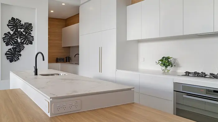 A kitchen with a sink, stove, and a painting on the wall.