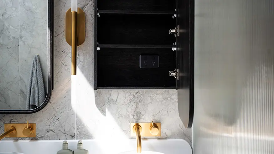 Modern bathroom vanity with black cabinet and gold fixtures.