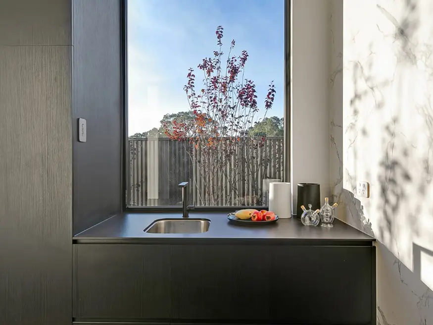 Sunny kitchen sink with window and plate of fresh fruit.