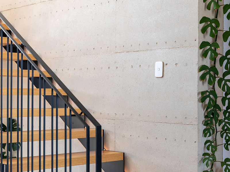 A staircase featuring a lush plant and a white switch on a wall