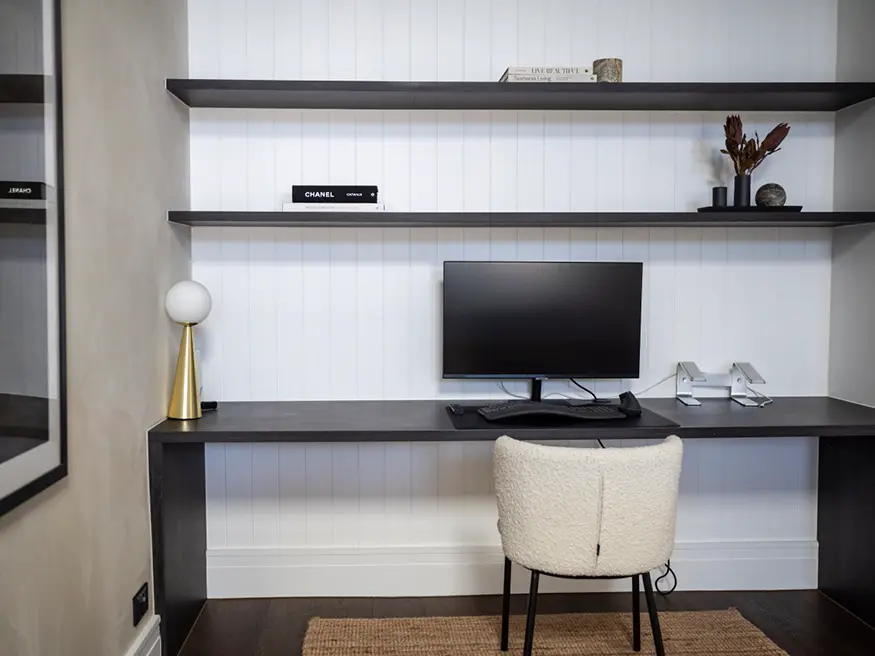 Desk in modern home office with black chair.