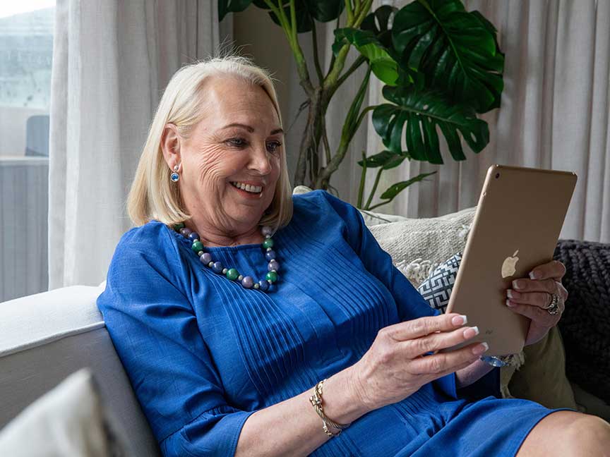 Woman seated on a couch, using an iPad