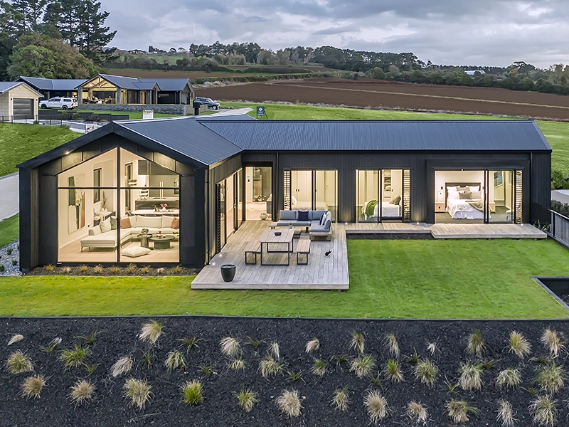 Modern house with large windows, surrounded by grass and landscaped yard