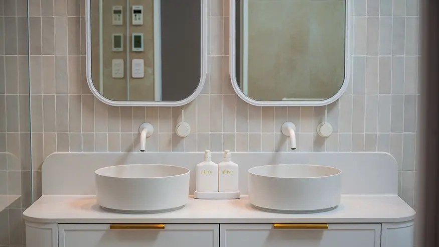 Bright white bathroom with double sinks and mirrors.