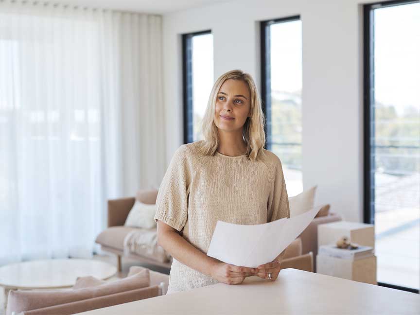 A woman in a brightly lit home considering their home renovation plans.