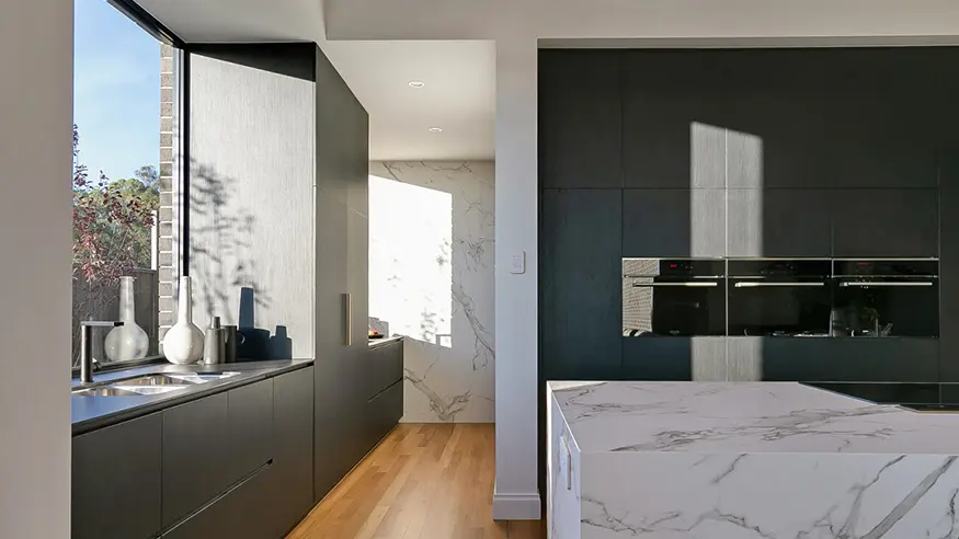 Modern kitchen with black cabinets and marble counters.