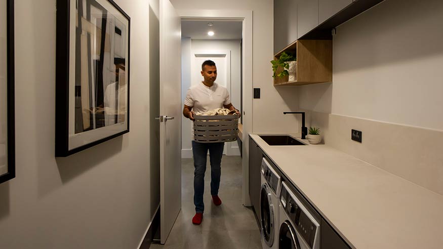 Man with a basket of clothes heading towards the laundry room