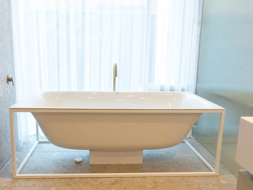 Freestanding white bathtub in a bright bathroom.