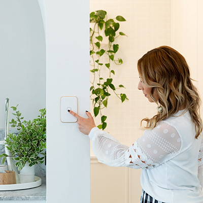 Woman presses the on button of Iconic Essence arctic white switch