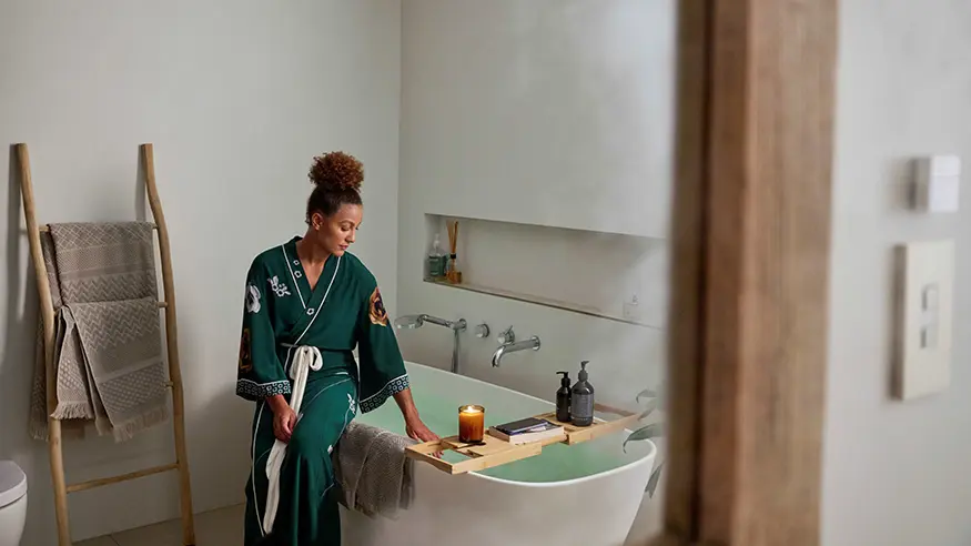 Woman with hair up relaxes in bathtub.