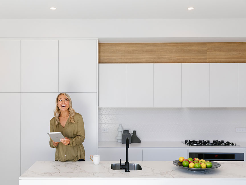 A woman in a modern kitchen holding a tablet.