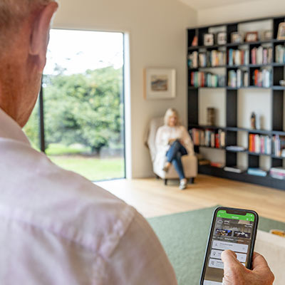 Man adjusts dining room lights with Wiser by SE app on smartphone