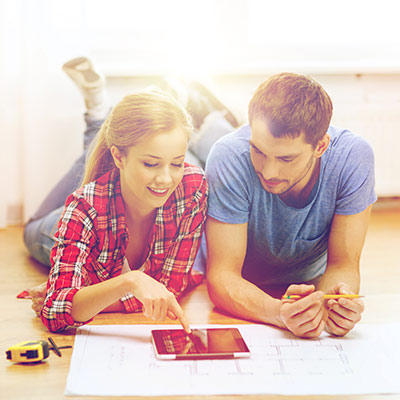 Couple smiles while planning renovation on a tablet device