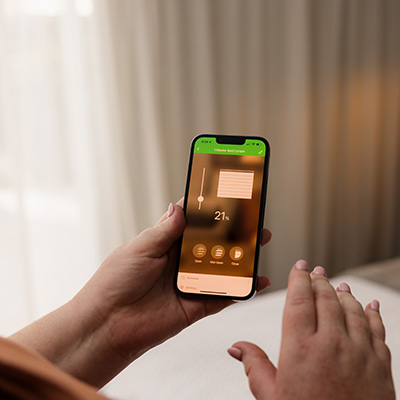 Woman's hand holding phone with blinds in the background