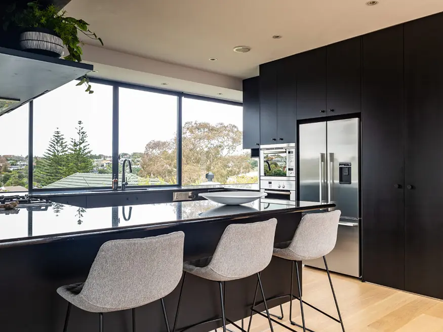 Modern kitchen with black cabinets and stainless steel fridge.