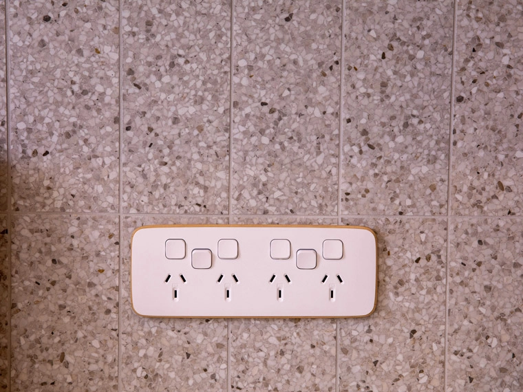 Modern pink electrical socket panel with multiple outlets, mounted on a textured gray terrazzo wall