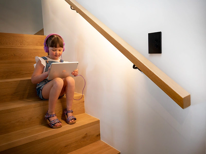 Kid sitting on a stairs playing with her tablet