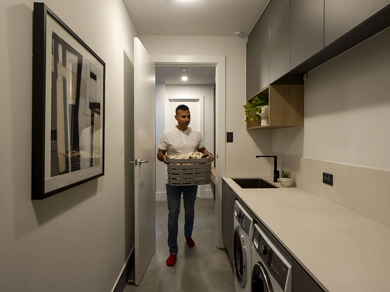 Man holding a laundry basket inside a cozy laundry room