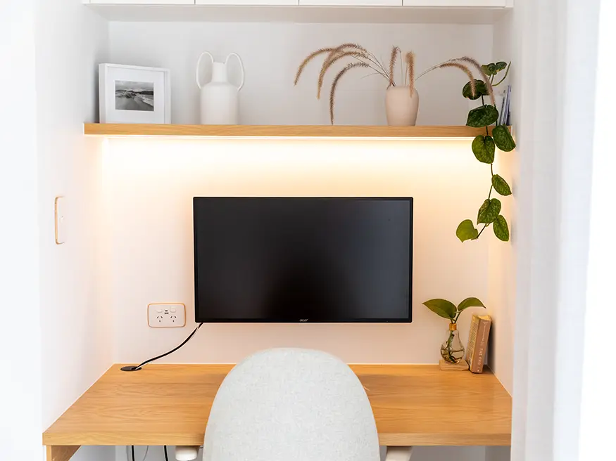 Home office with desk, chair, shelves, and wall décor.