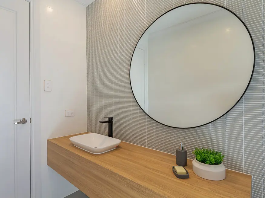 Bathroom vanity with round mirror and chrome faucet.